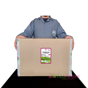 Persona con bata de laboratorio de la marca EcoAndes sosteniendo una caja de 25 kg de Espirulina en polvo. El empaque muestra una etiqueta con información del producto, certificaciones ecológicas y sello de calidad y envasado artesanal.