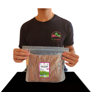 Persona con camiseta de la marca EcoAndes sosteniendo una bolsa transparente con cierre zip de 1kg de Canela en rama. El empaque muestra una etiqueta con información del producto, certificaciones ecológicas y sello de calidad y envasado artesanal.
